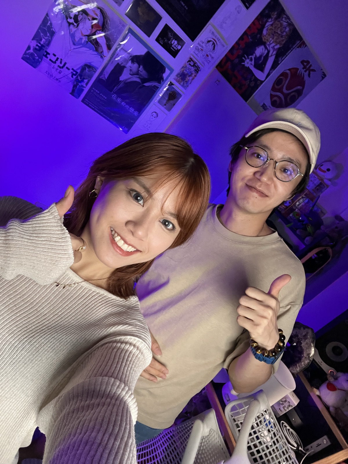 紫色燈光的工作室裡兩個人靠在一起合照，其中一人比出大拇指。